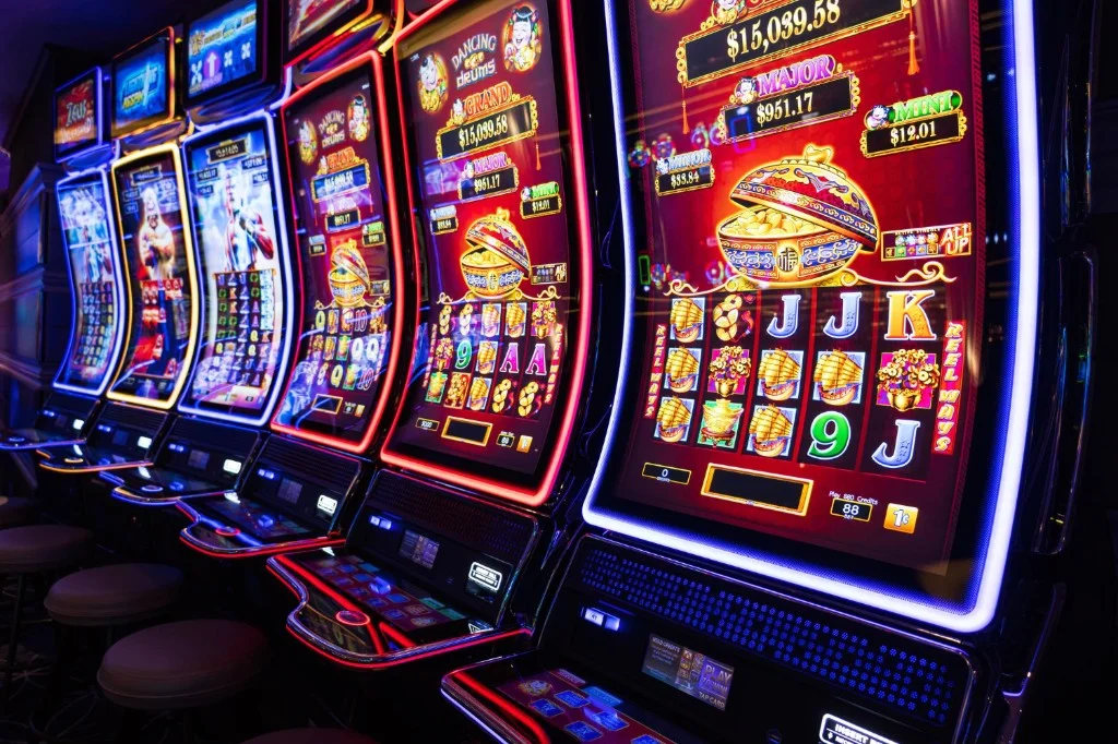 Row of lit slot machines on a casino floor — featured image for the PHJoy bonus terms guide